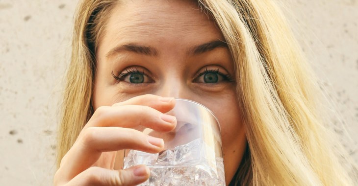 Tjej dricker vatten ur ett glas.