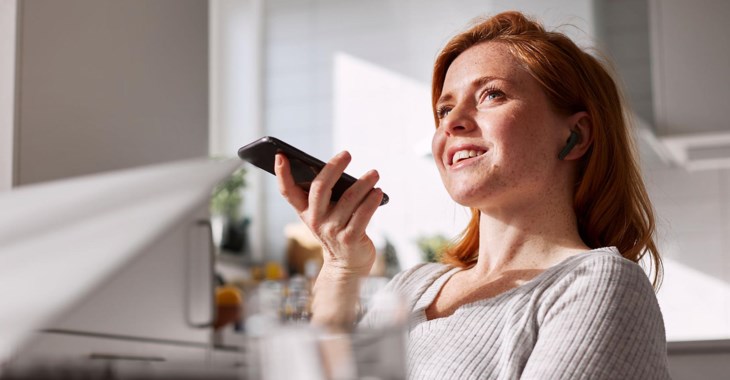 Kvinna framför dator pratandes i mobiltelefon.