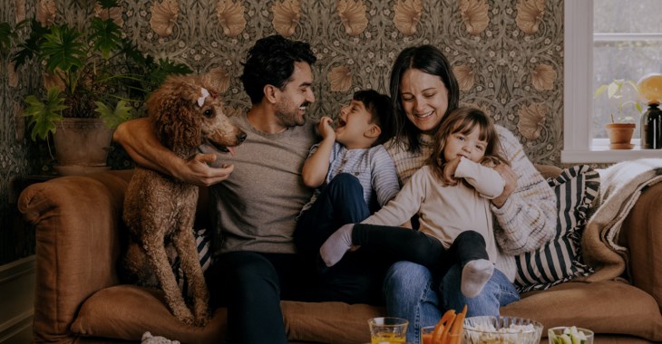 Familj med hund och barn som samlats i soffan.