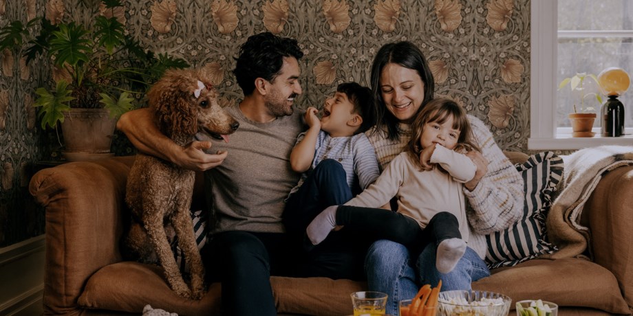 Familjen med hund och två barn är samlade i soffan.
