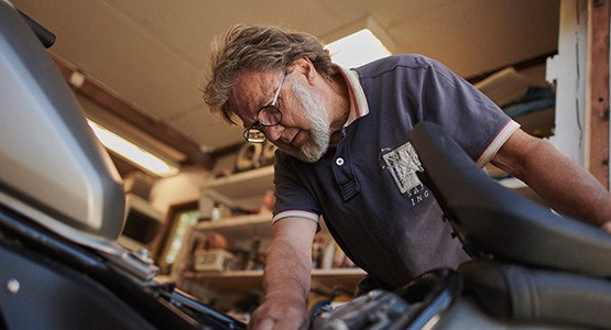 Man i garage med motorcykel.