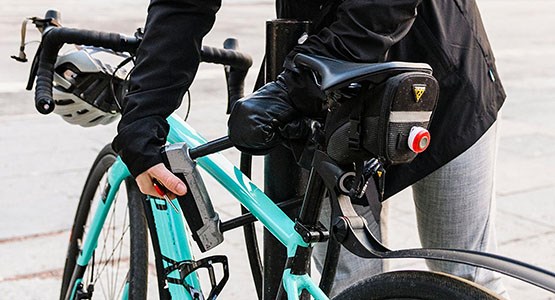 Kvinna låser cykel med bygellås.