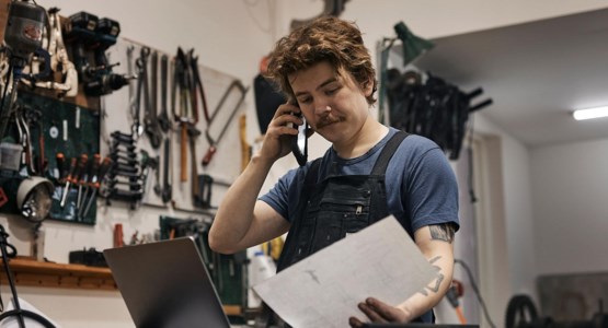 Man i verkstad arbetar vid dator.