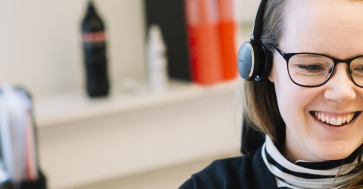 Bild på glad kvinna som sitter i telefon med kund