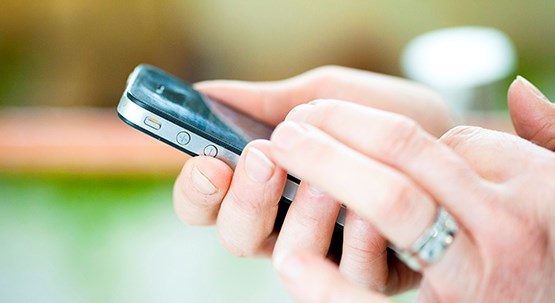 Händer som håller en mobiltelefon.