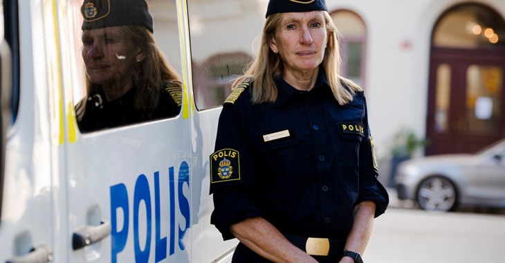 Kvinnlig polis i uniform står utanför en polisbil