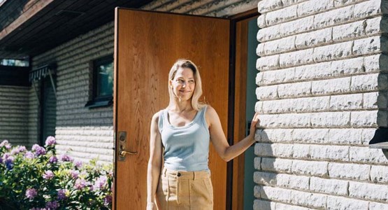 Kvinna står på farstutrappan utanför mexitegelvilla.