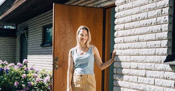 Kvinna står framför tegelvilla. 