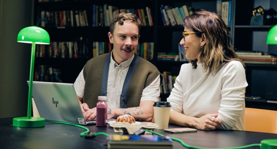 Två personer sitter med en laptop. 