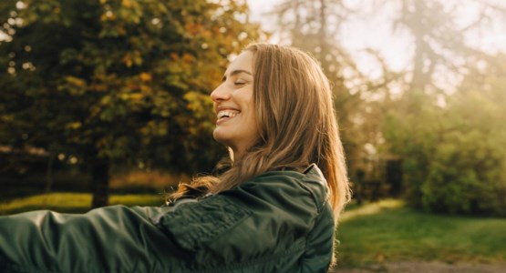 Foto av glad kvinna i solnedgång.