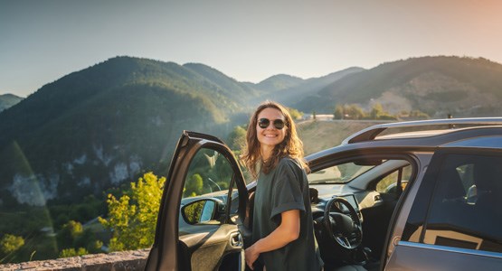 Tjej som står vid en bil.