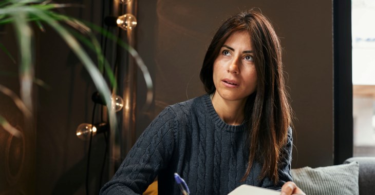 Kvinna sitter vid bord och ser fundersam ut