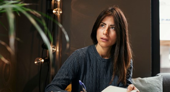 Ung kvinna sitter vid bordet och ser fundersam ut 