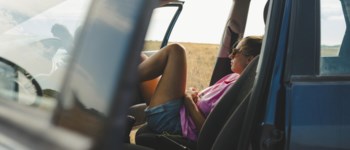 Tjej i framsätet av parkerad bil.