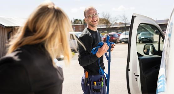 Man i arbetskläder står vid sin tjänstebil.