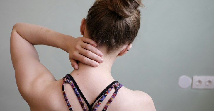 En kvinna håller handen över nacken.