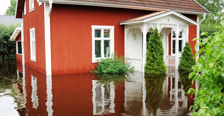 Ett rött hus med översvämmad trädgård