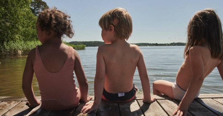 Ryggar på tre barn som sitter på en brygga.