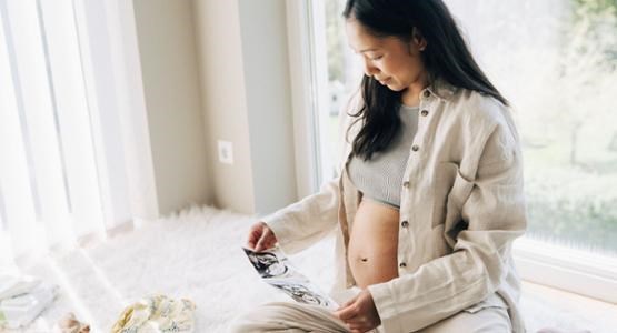 Gravid kvinna ligger i partnerns knä i soffan.