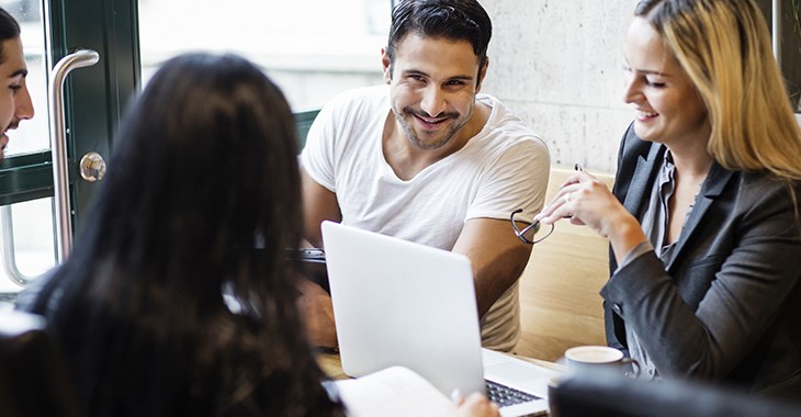 fyra personer sitter runt ett bord och skrattar. bild.