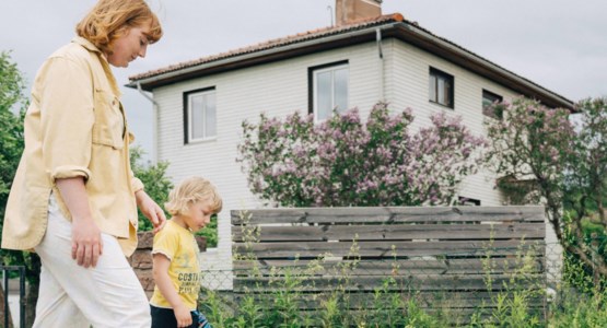 Kvinna och liten pojke går utanför villa.