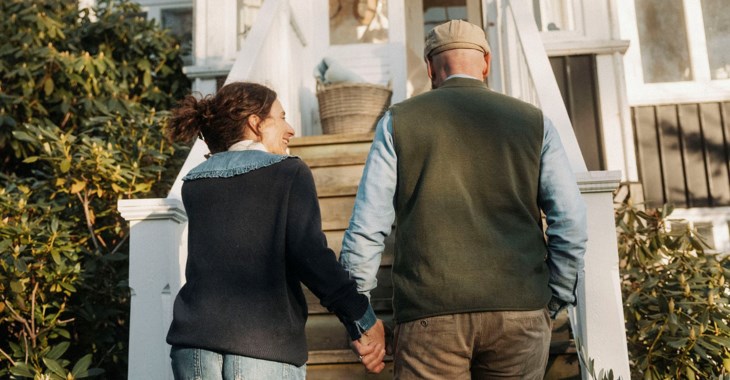Ett äldre par går hand i hand uppför trappan till sitt hus