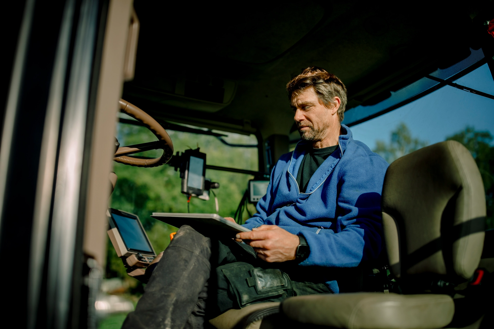 Man sitter i traktor och arbetar på surfplatta.
