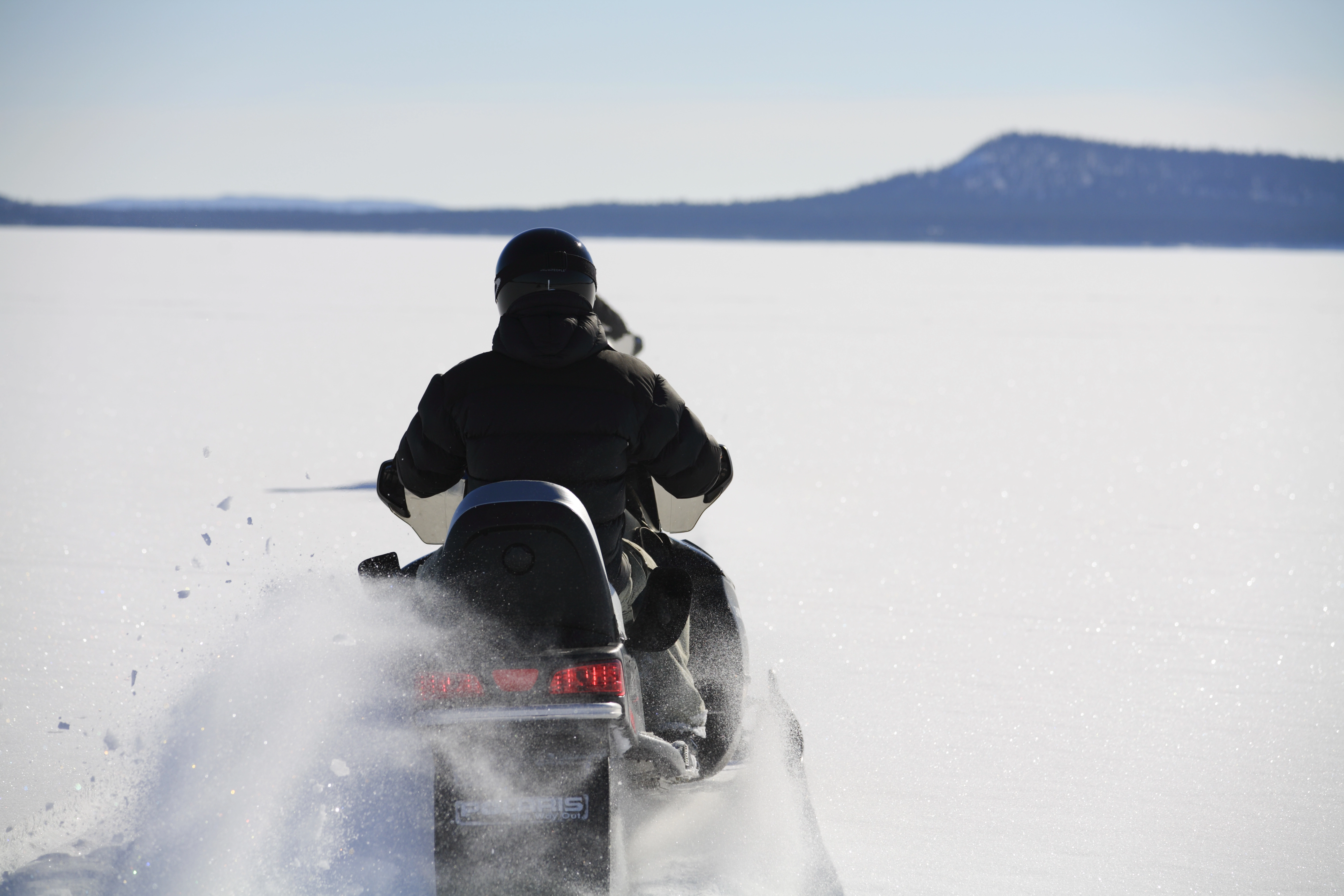 Person på snöskoter i vidsträckt snölandskap.