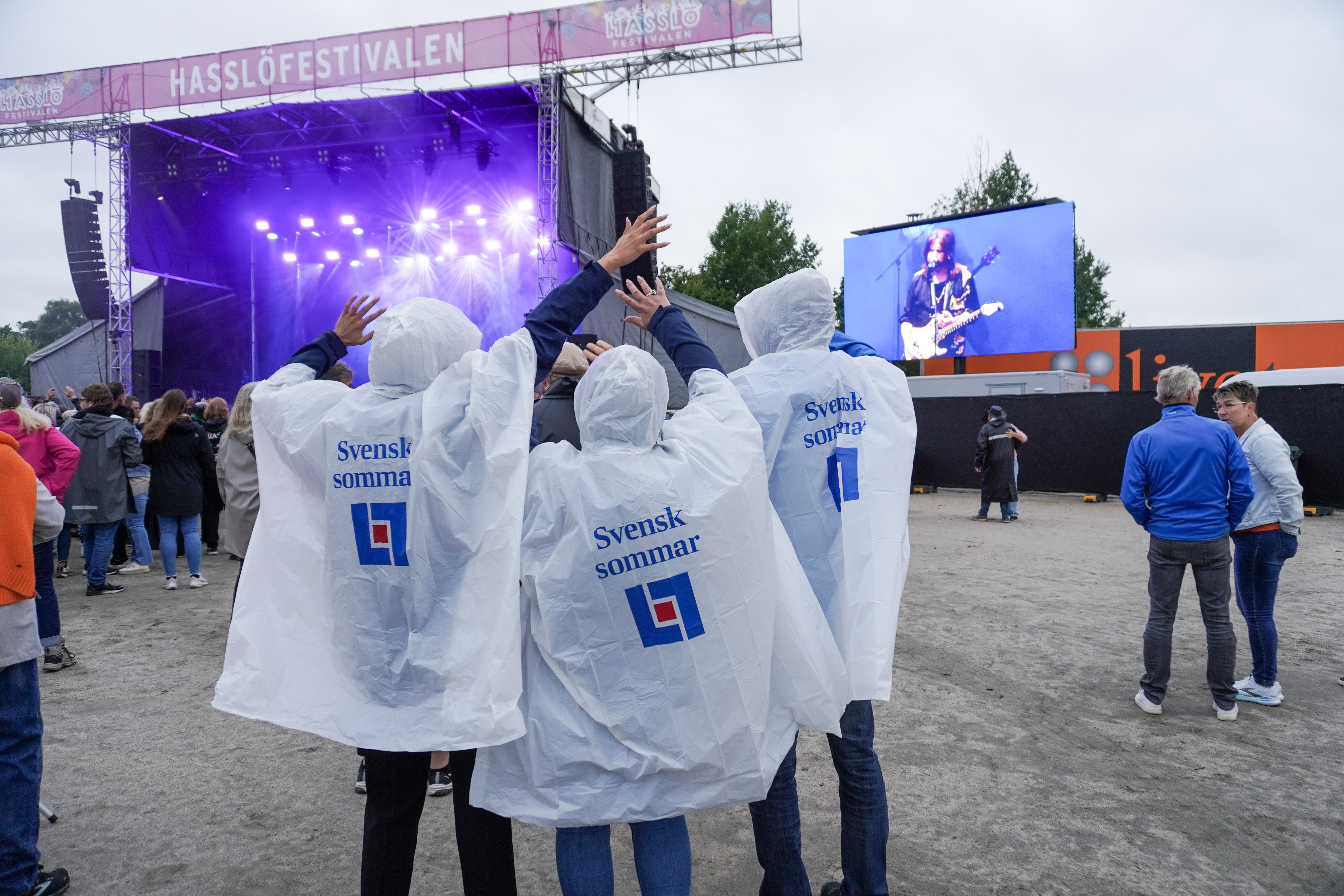 tre personer i regnponchos på festival