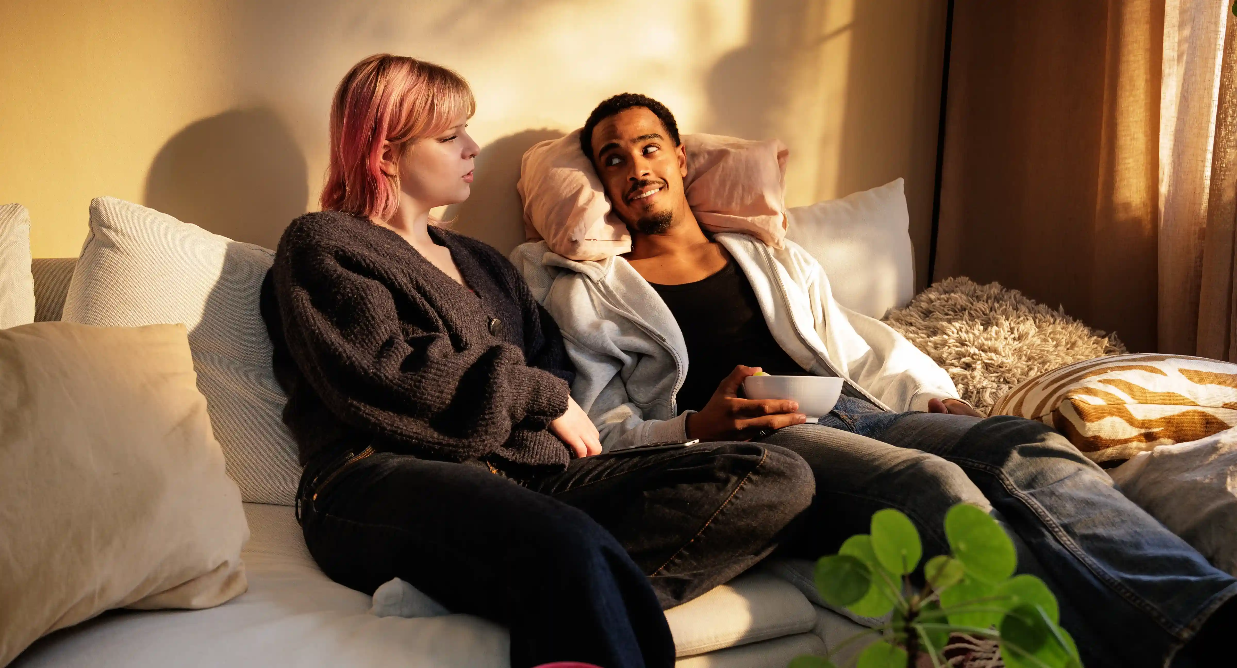 Ett ungt par sitter i soffan och diskuterar sin ekonomi.