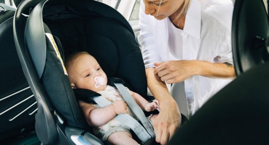 En liten bebis sitter i en bakåtvänd bilbarnstol.