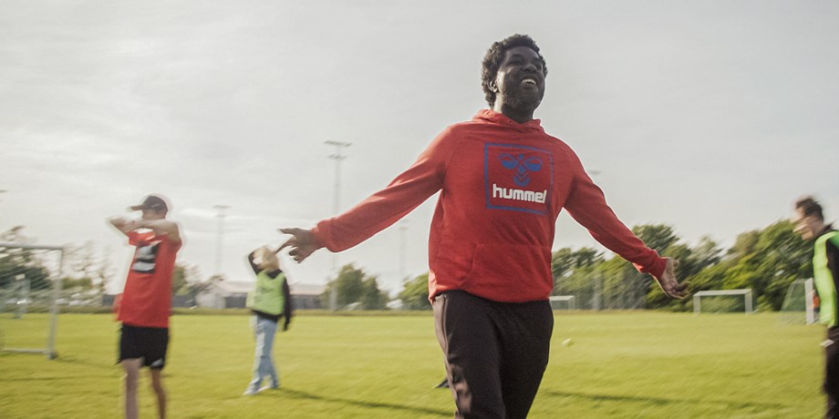 En ung kille gör en målgest på fotbollsplanen.