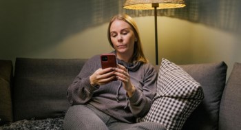 En tjej sitter i en soffa och scrollar på sin mobil.