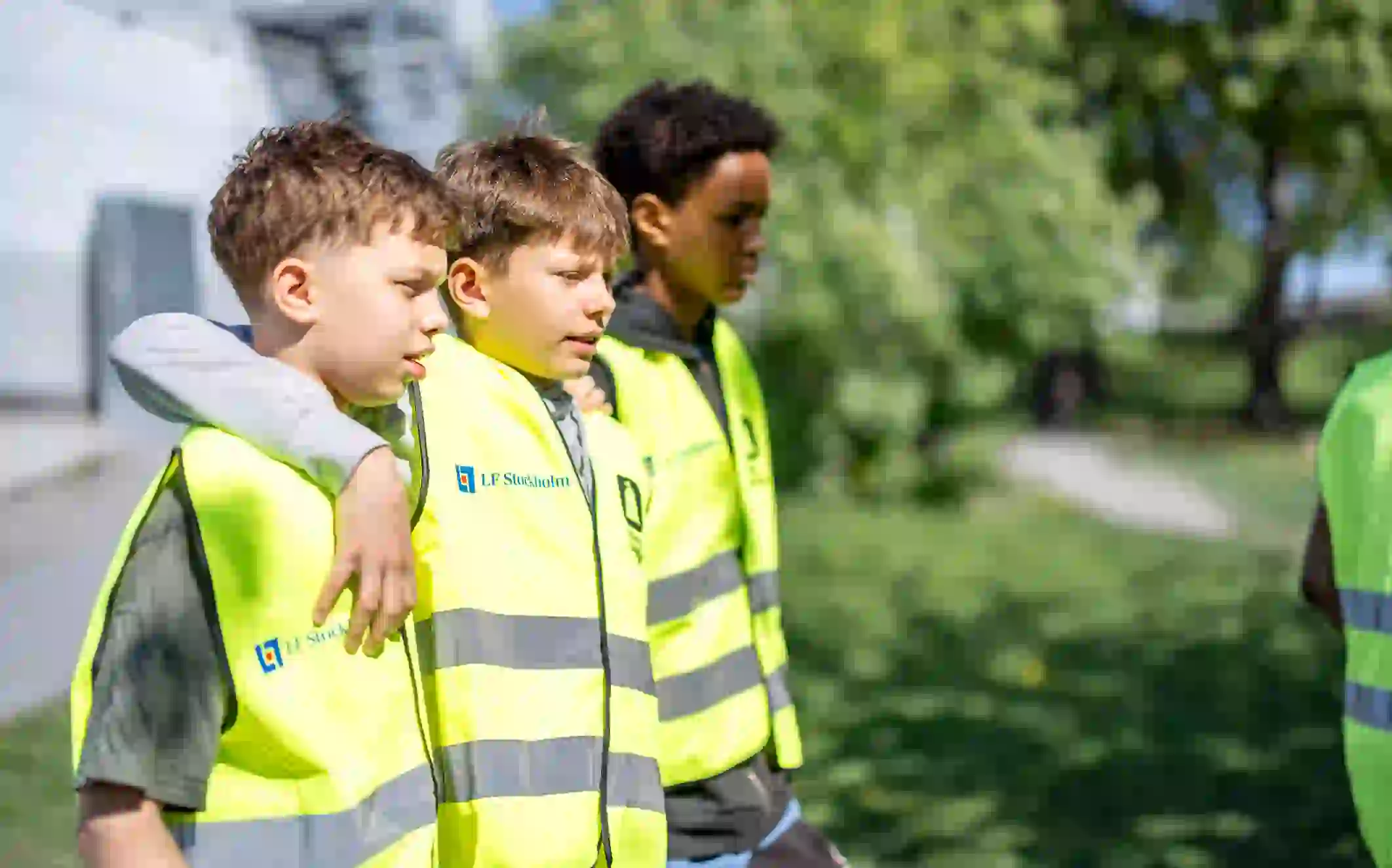 Barn står i en park med reflexvästar