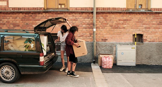 tjejer lyfter flyttkartonger ur bil