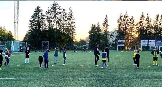 Fotbollsplan i solnedgång med barn som tränar