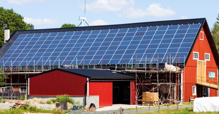 Ladugård med nyinstallerade solceller på taket. En byggnadsställning står längs byggnaden.