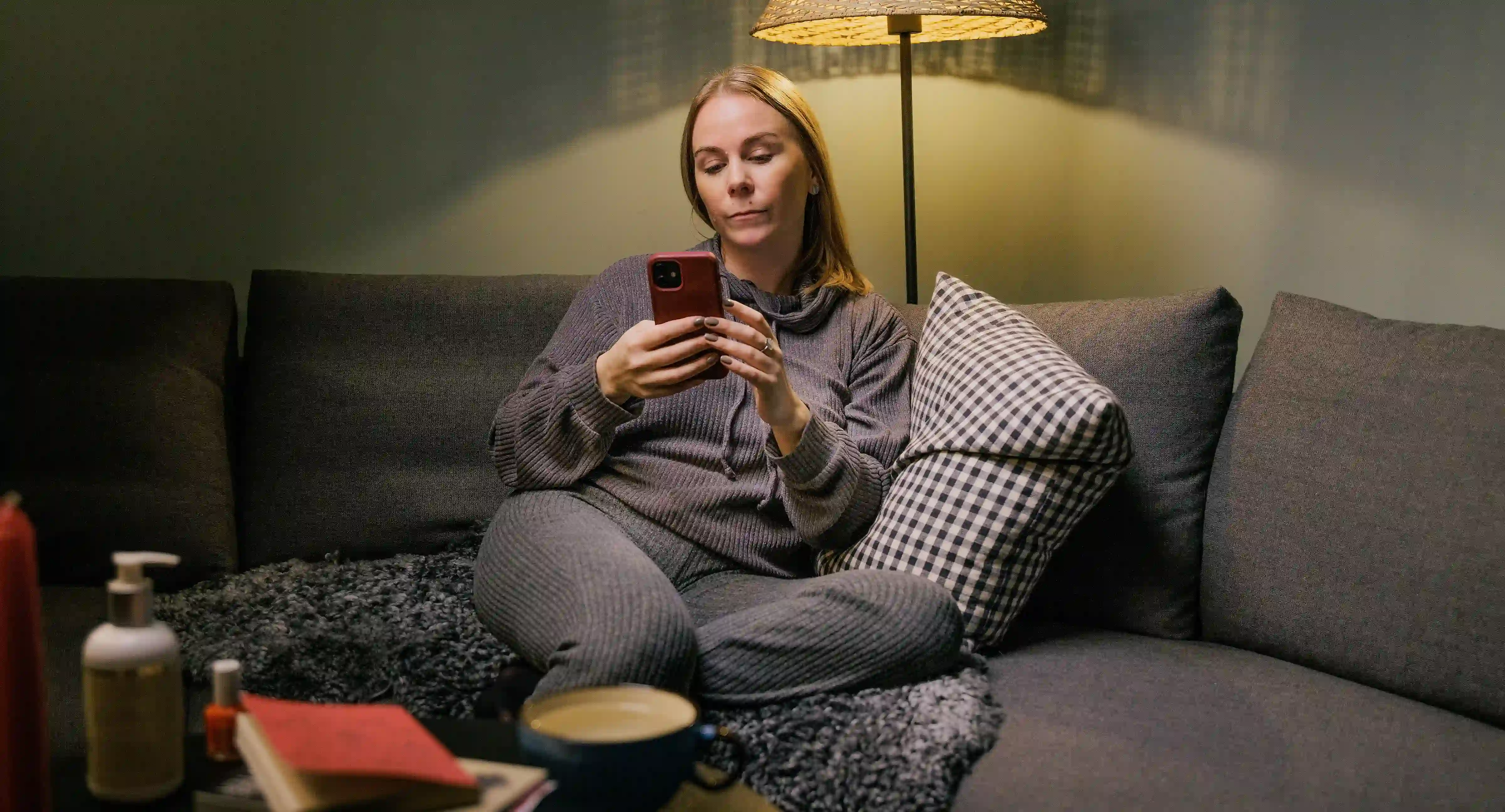 Kvinna sitter och gör en budget i mobilen.