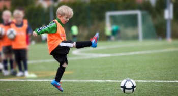 En liten pojke tränar fotboll tillsammans med sitt lag.