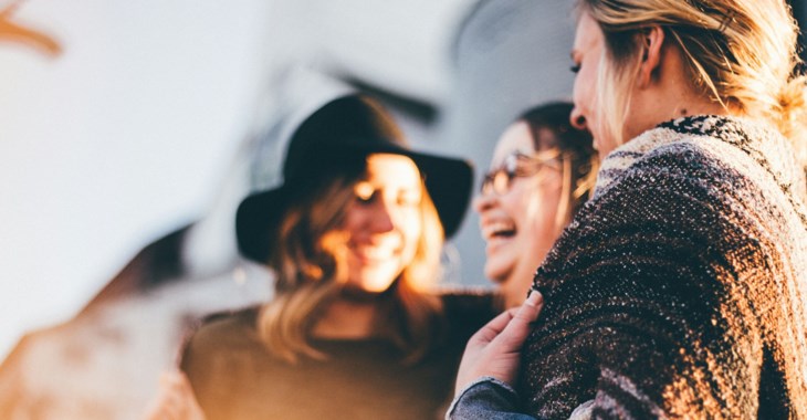 Tre kvinnor som skrattar tillsammans.