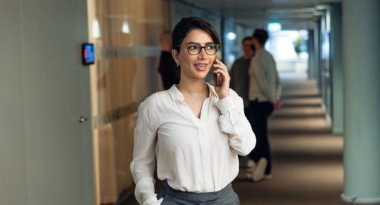 Kvinna som pratar i mobil i kontorsmiljö.