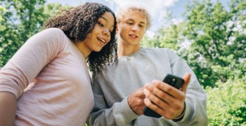 Två ungdomar tittar gemensamt i en mobiltelefon.