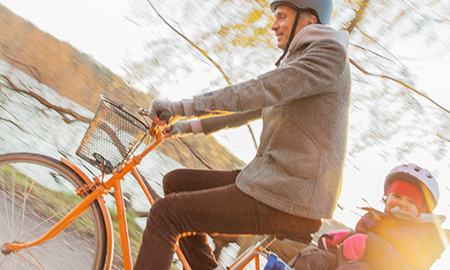 En pappa cyklar med ett litet barn.