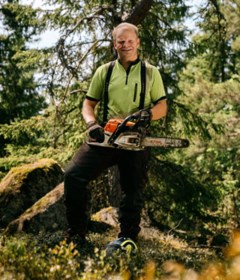 Per Solberg står i sin skog med en motorsåg.