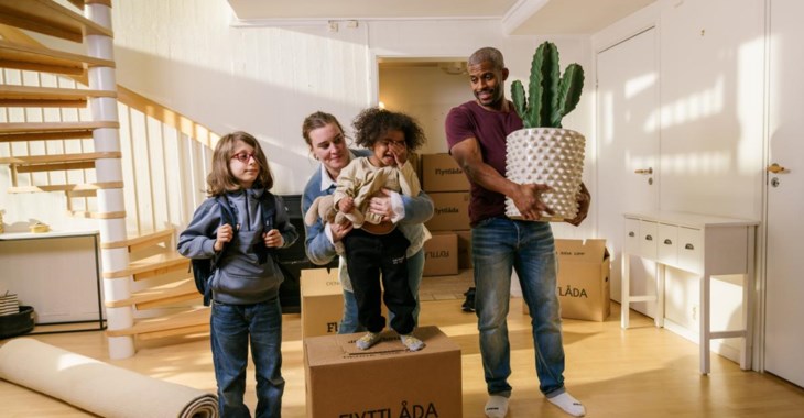 Två unga kvinnor lyfter ut flyttlådor ur bagageluckan på en bil.