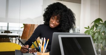 Kvinna  vid dator i kontorsmiljö.