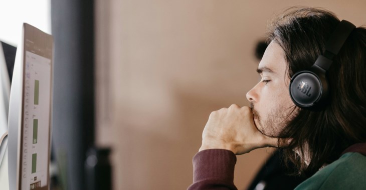 Kille med hörlurar som sitter framför en bildskärm.