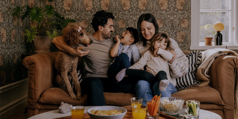 Familjen med hund och två barn är samlade i soffan.