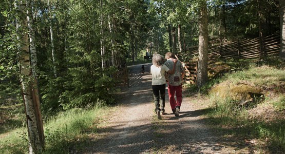 Äldre par som promenerar på en landsväg och håller om varann.