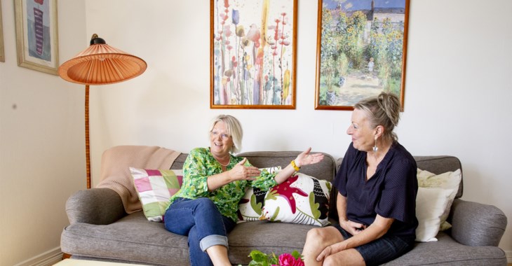 Jobbonärerna Eva och Kerstin sitter i en soffa i ett vardagsrum och pratar glatt.